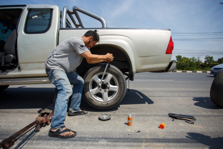 A man changing the wheel at the side of the road