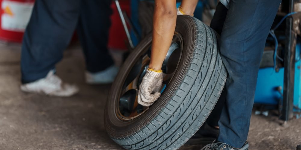 close up Car mechanic replace tire on wheel in auto repair service workshop.