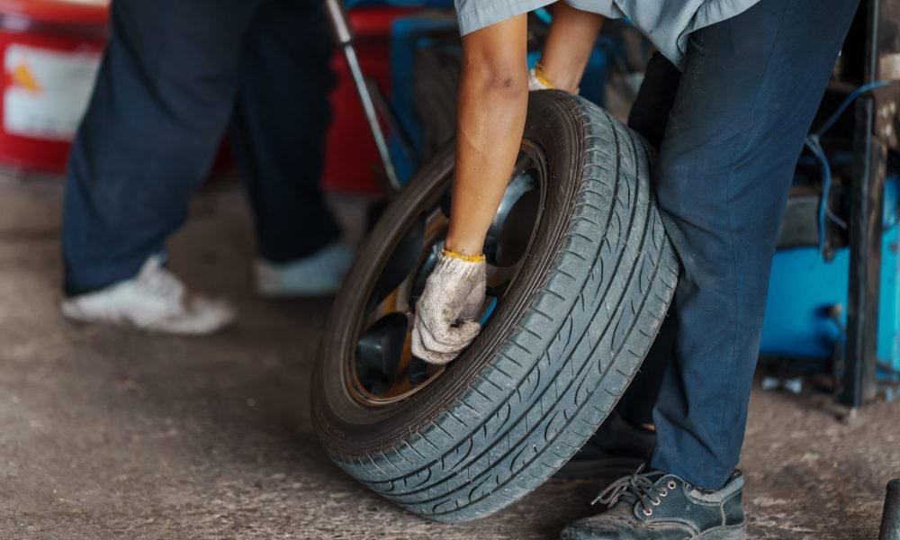 close up Car mechanic replace tire on wheel in auto repair service workshop.