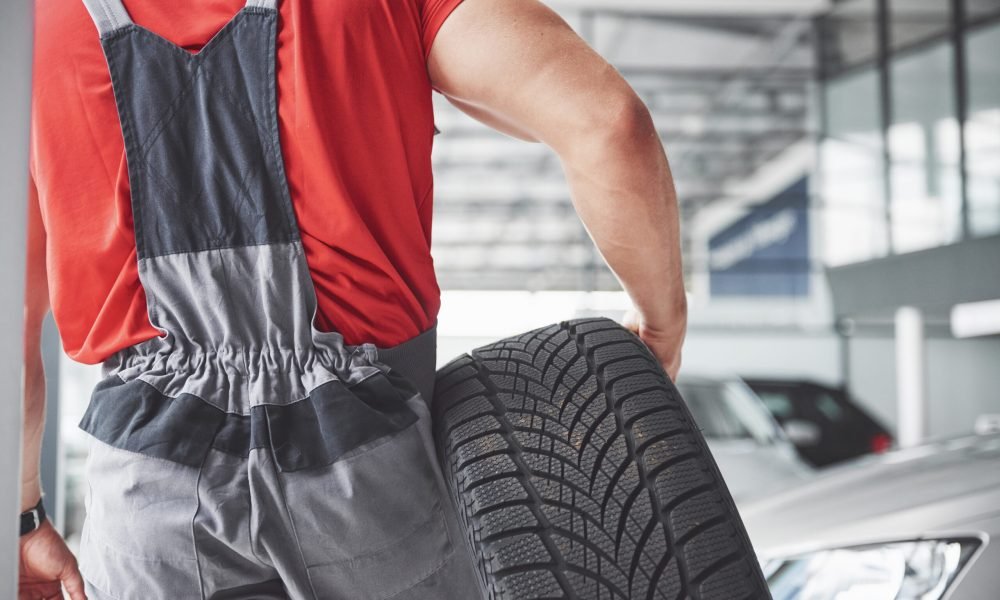 Mechanic holding a tire tire at the repair garage. replacement of winter and summer tires.